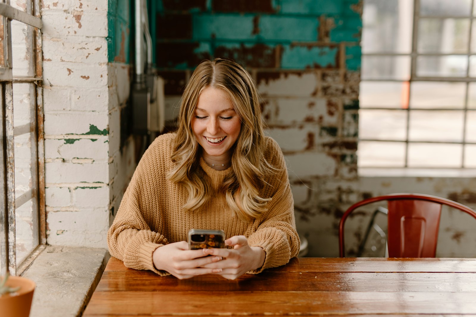 Clienta sonriendo mientras usa una app en su teléfono en un café