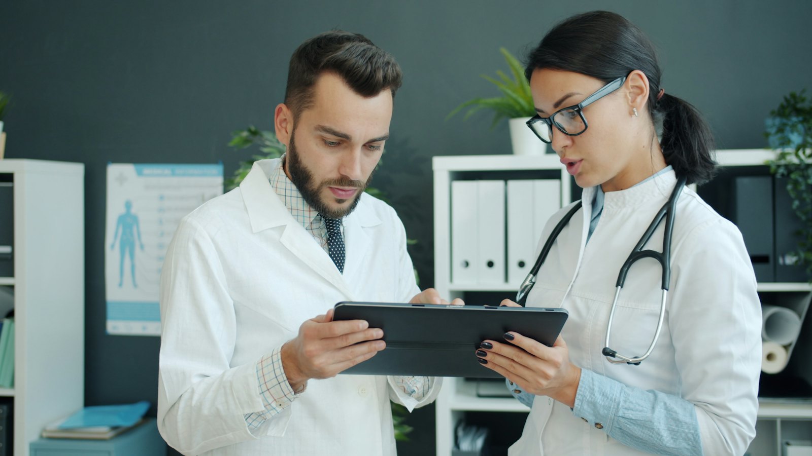 Dos médicos revisando juntos una tableta en el consultorio