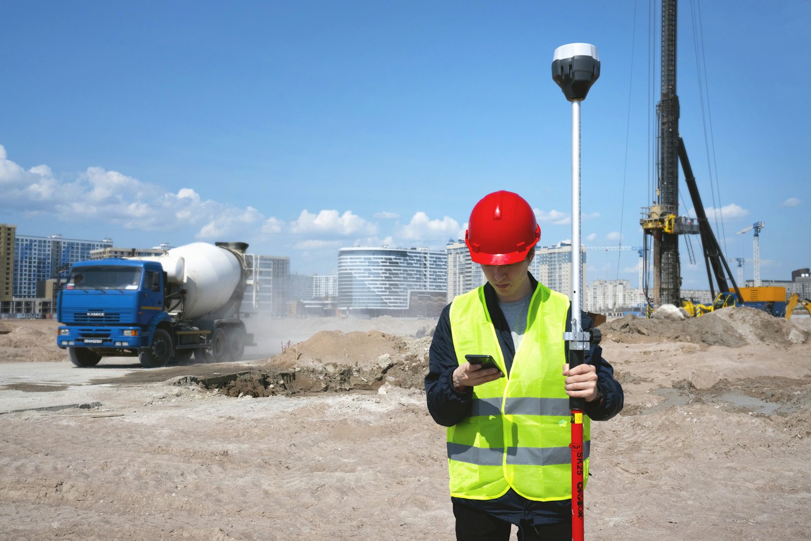 Supervisor con casco y chaleco revisando su teléfono en una obra